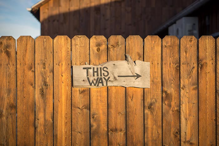 Panneau "This way" (par ici) sur palissade en bois