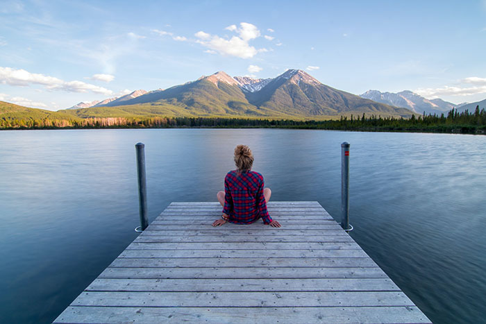 Sérénité, personne assise dans un cadre apaisant devant un lac et une montagne