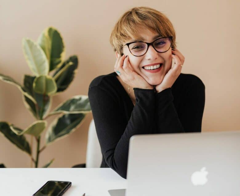 femme devant un ordinateur à côté d'une plante sourire lunettes jeune quel est le lien entre développement personnel et management