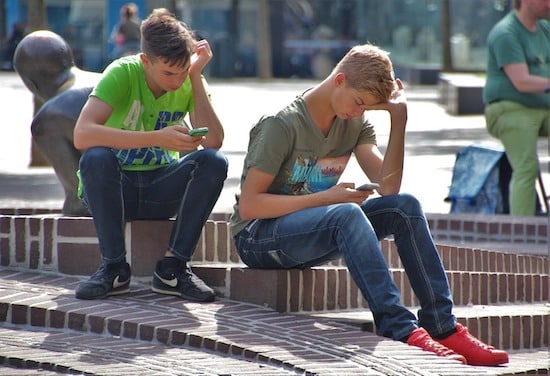 Deux jeunes assis occupés à leur téléphone portable sans communiquer entre eux